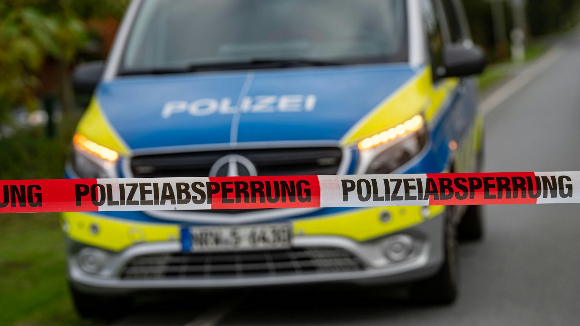 Polizeiauto hinter Polizeiabsperrband auf der Straße