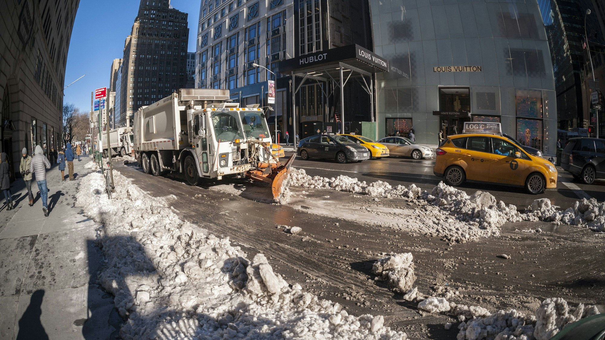 Schneeräumung auf einer Straße mit Gebäuden und Fahrzeugen