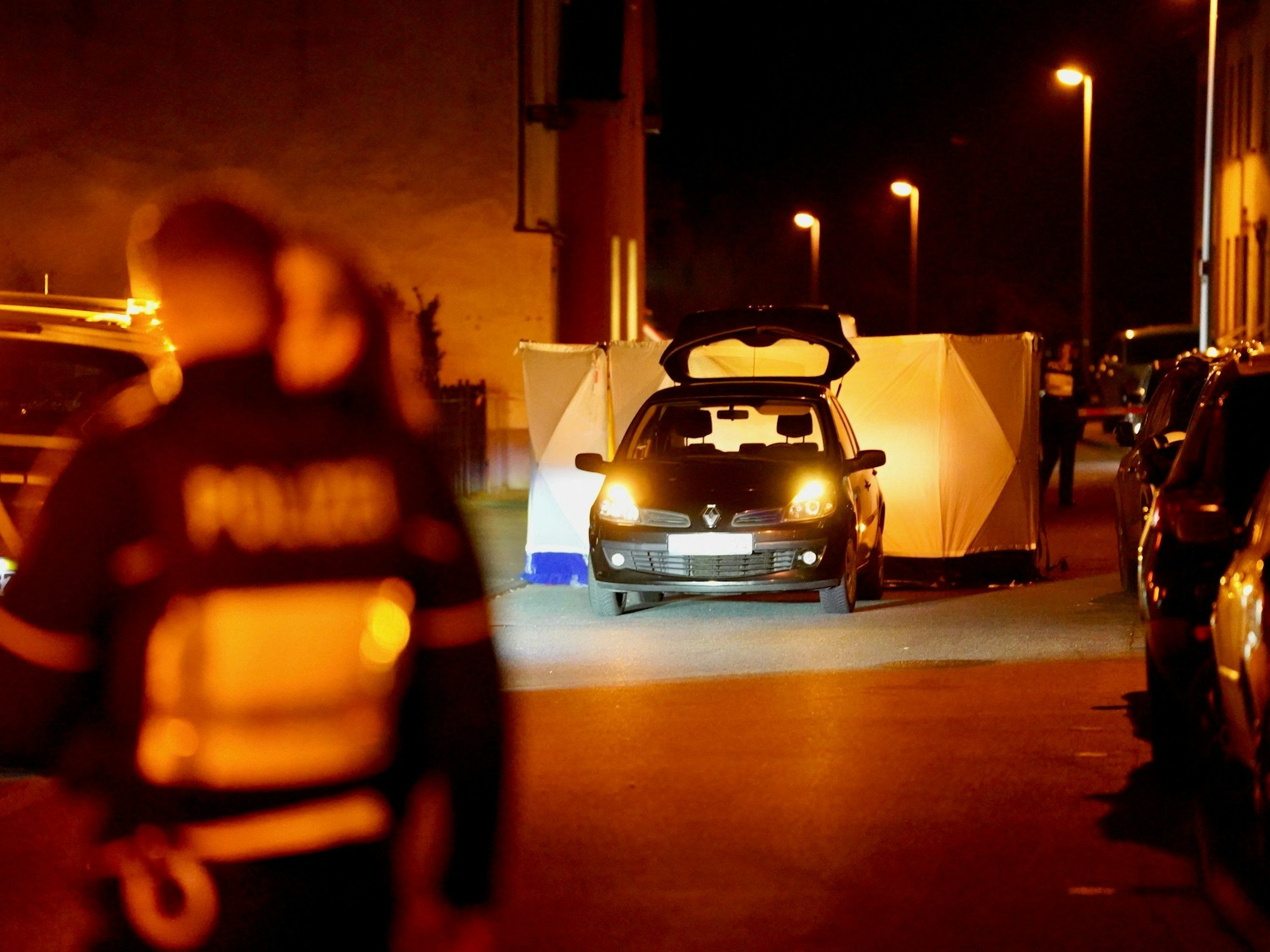 Ein Auto steht auf der Straße, die Polizei hat dahinter einen Sichtschutz aufgebaut.