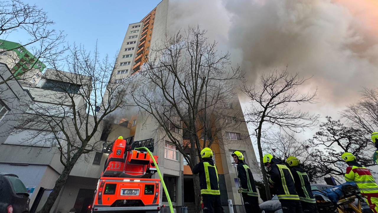 Einsatzfahrzeuge von Rettungskräften und Feuerwehr stehen vor einem Hochhaus, aus dem Rauch aufsteigt. In Berlin-Spandau brennt seit den frühen Morgenstunden ein Hochhaus.