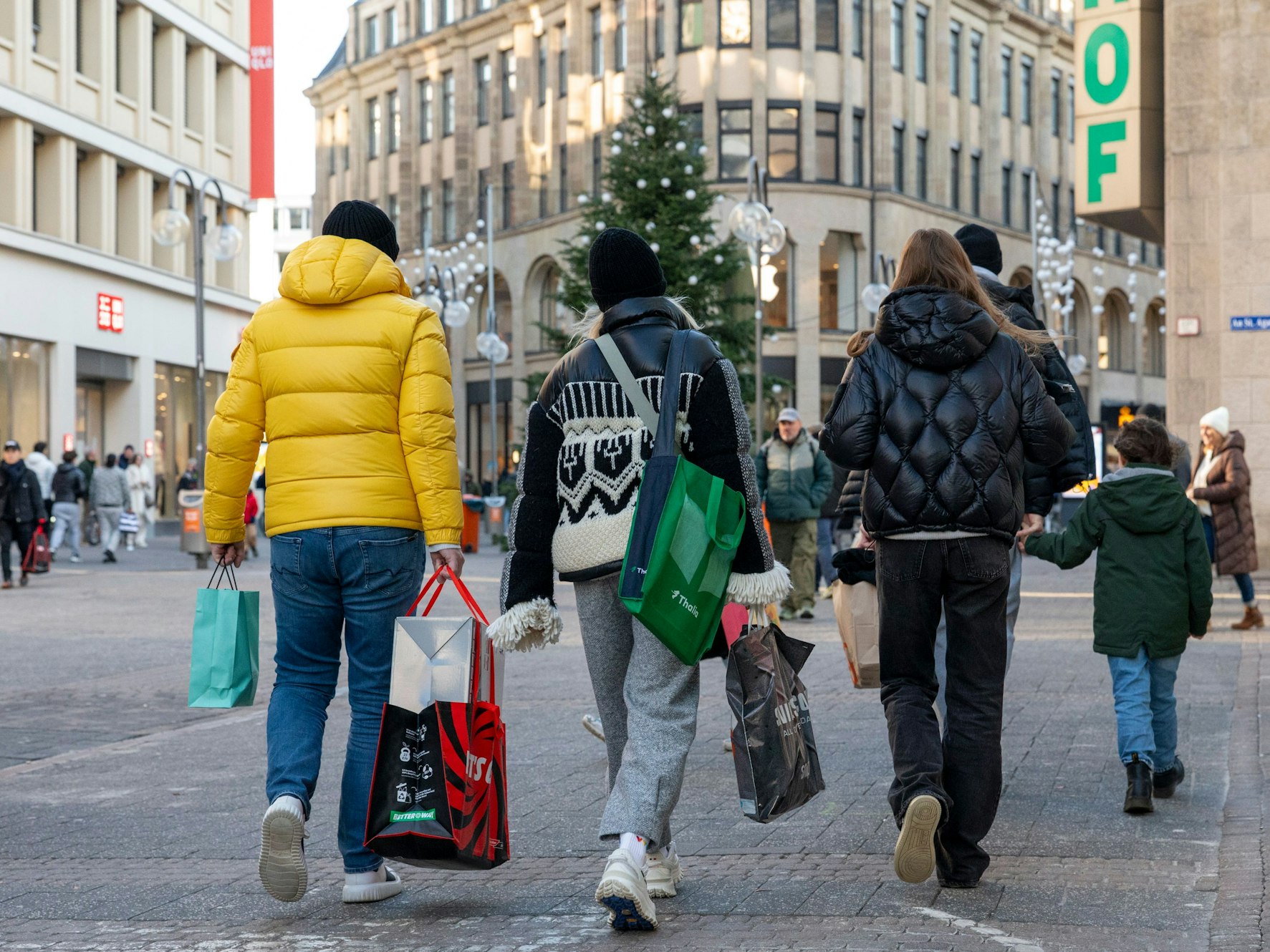 Personen mit Einkaufstüten in den Händen gehen über die Schildergasse.