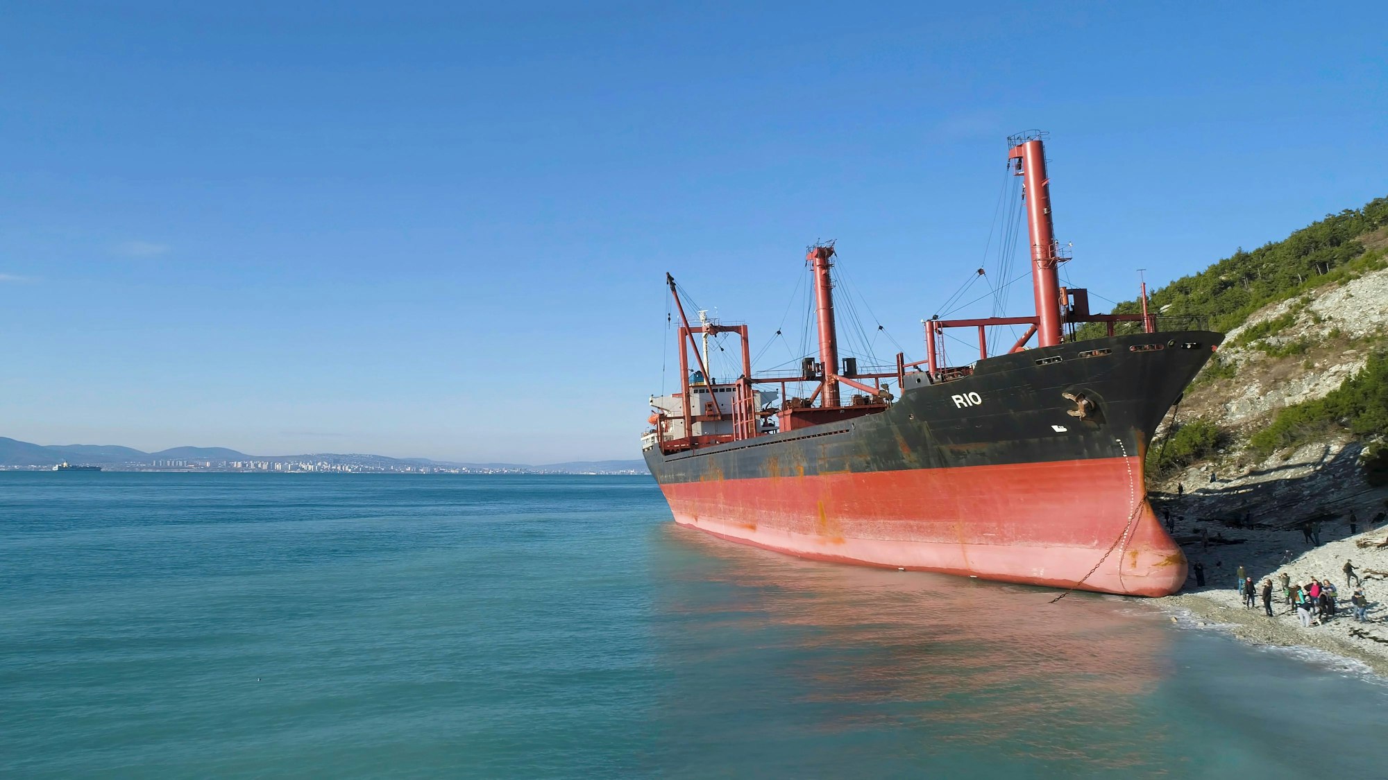 Gestrandetes Schiff am Meer mit Menschen am Ufer