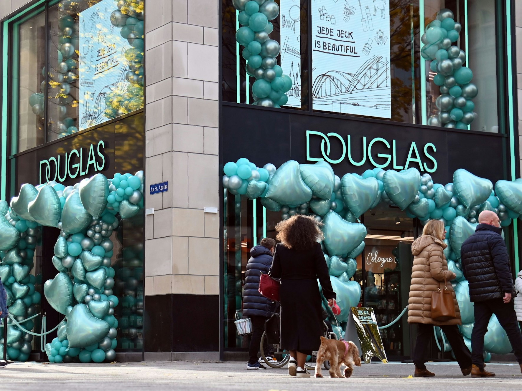 An den Eingängen einer Douglas-Filiale hängen zahlreiche Luftballons in Herzform.