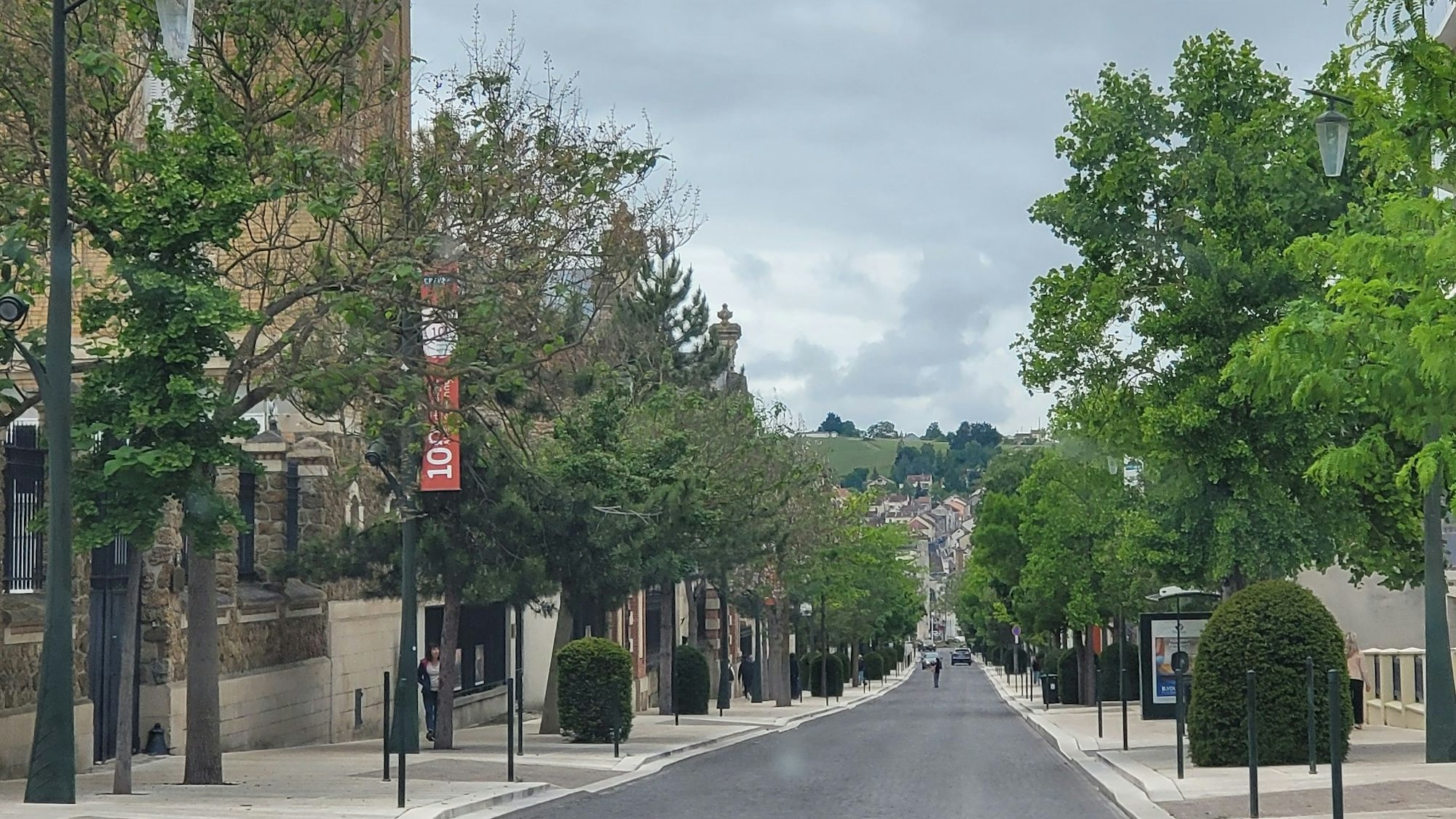 Eine lange Atraße gesäumt von Bäumen und Geschäften
