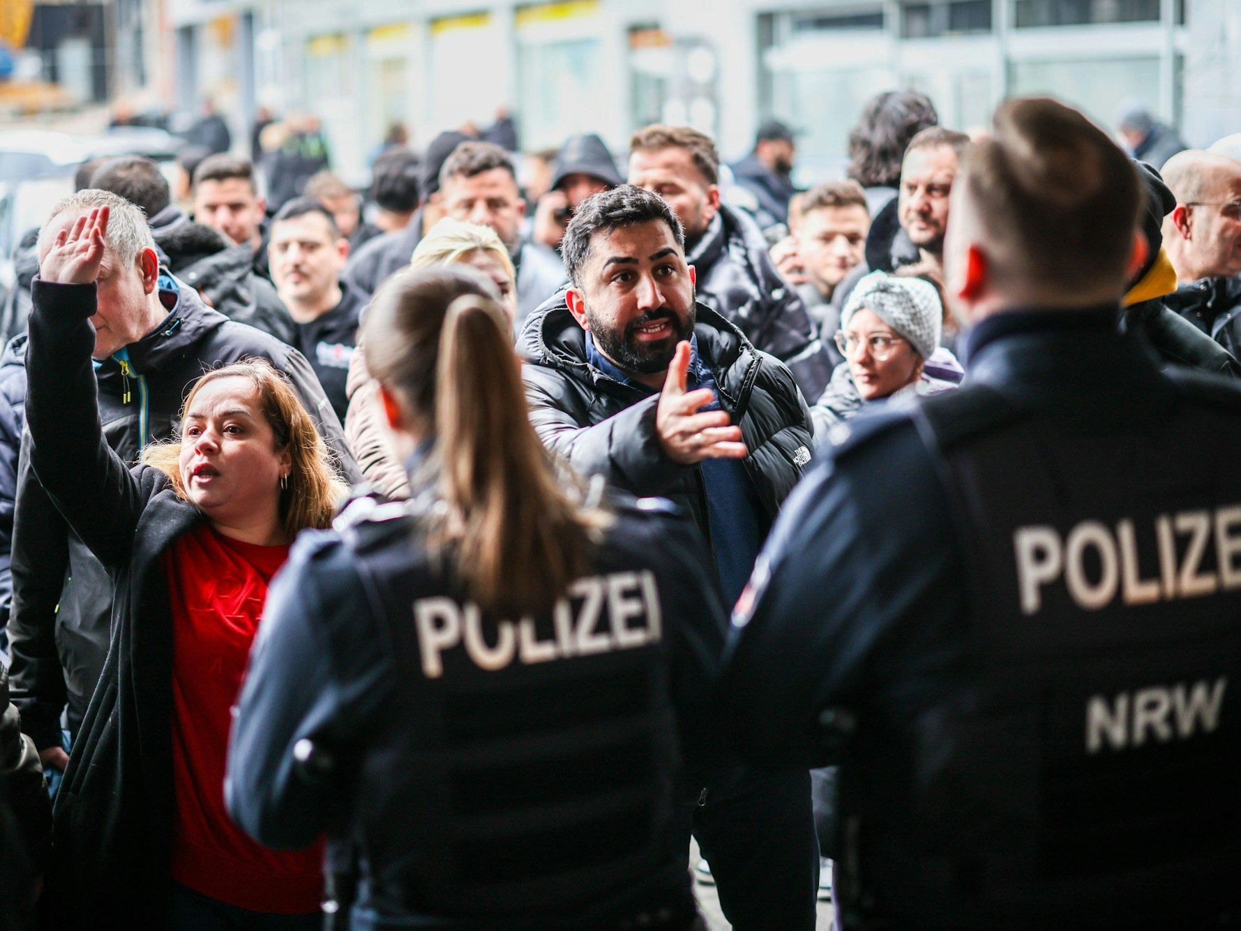 Aufgebrachte Kunden diskutieren vor der Sparkassenfiliale in Buer mit Polizeibeamten nach der Räumung des Vorraums der Filiale.