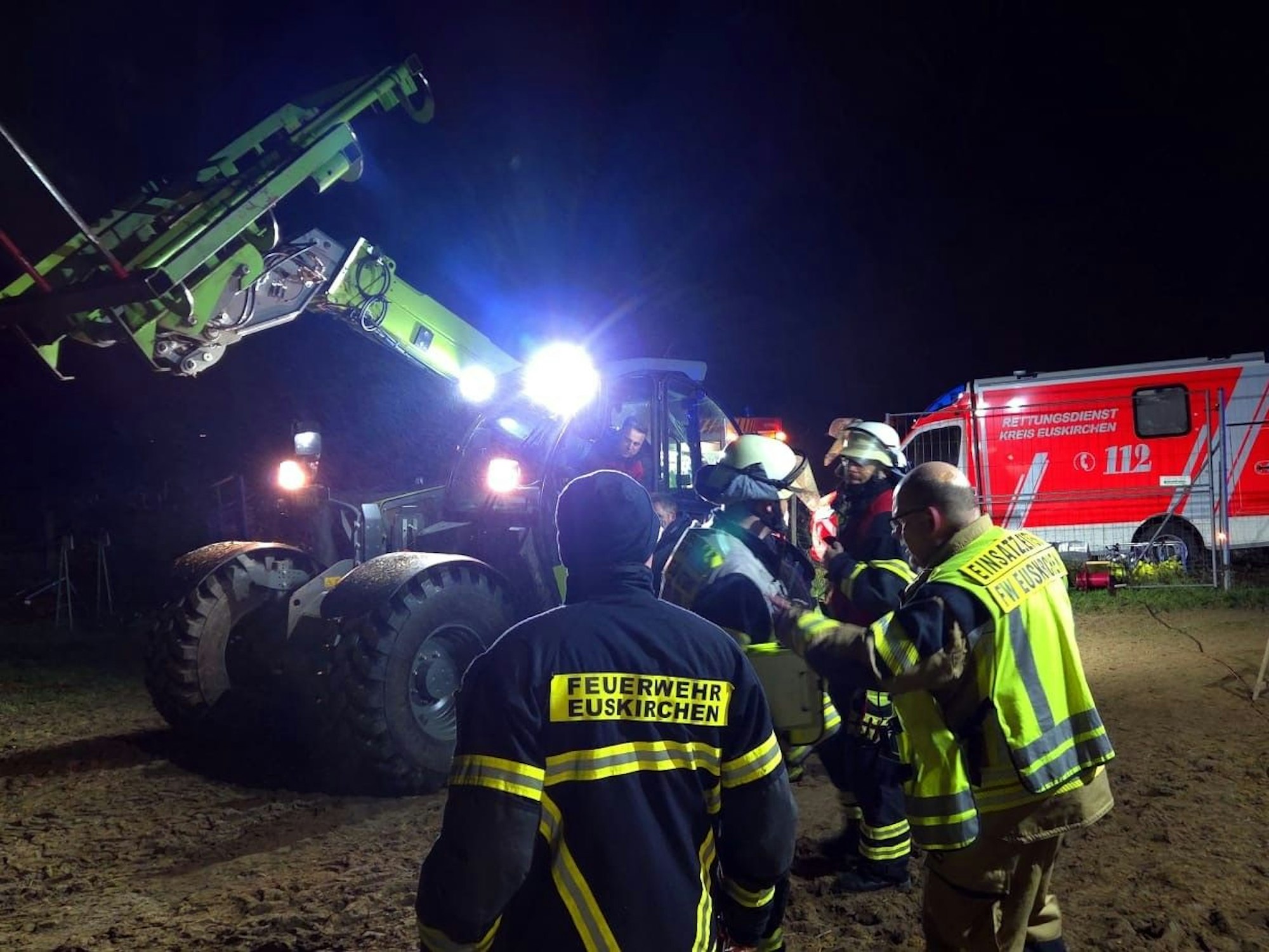 Einsatzkräfte der Feuerwehr stehen vor einem Radlader.