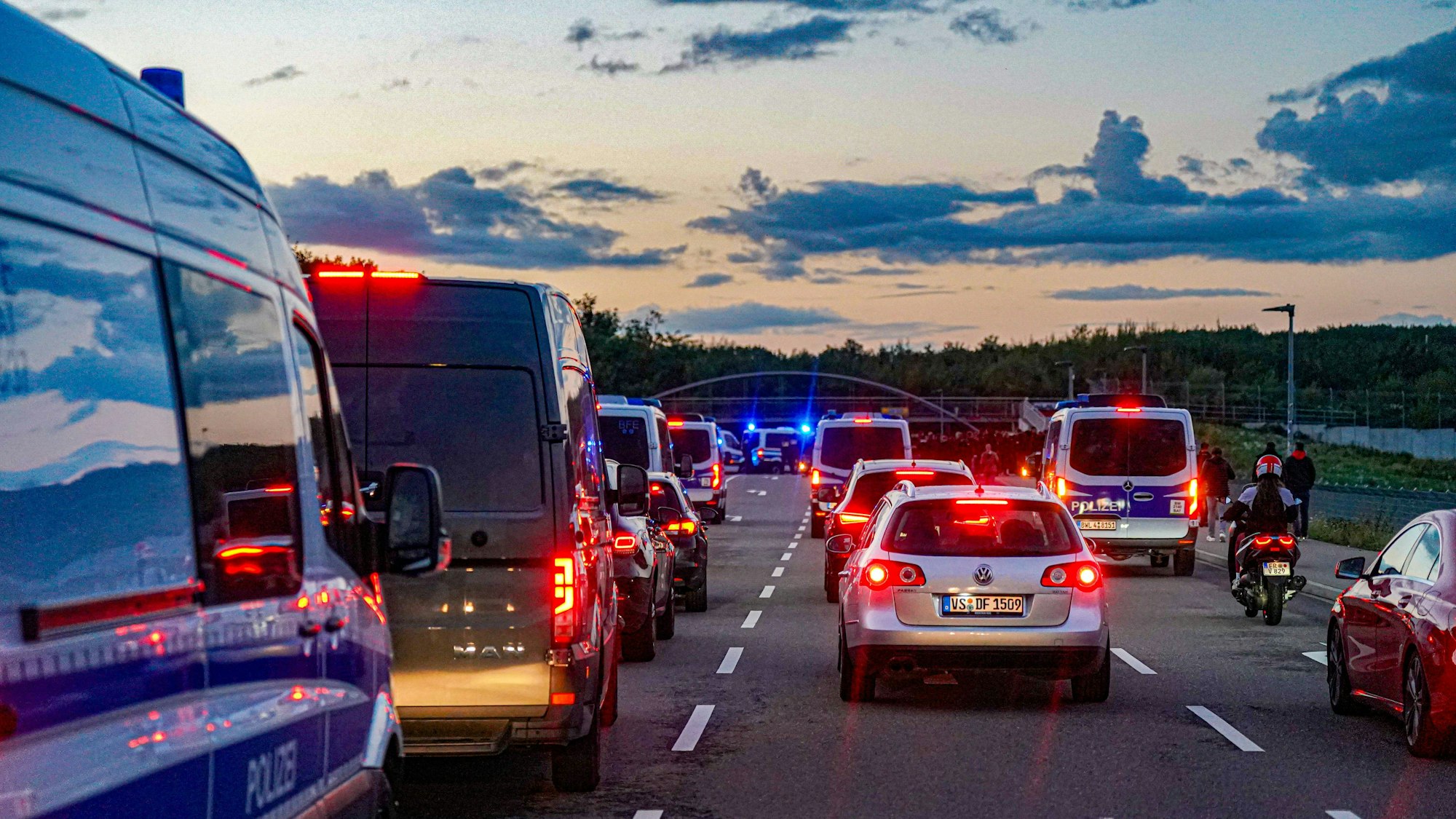 Polizeifahrzeuge und Verkehr auf einer Straße bei Dämmerung