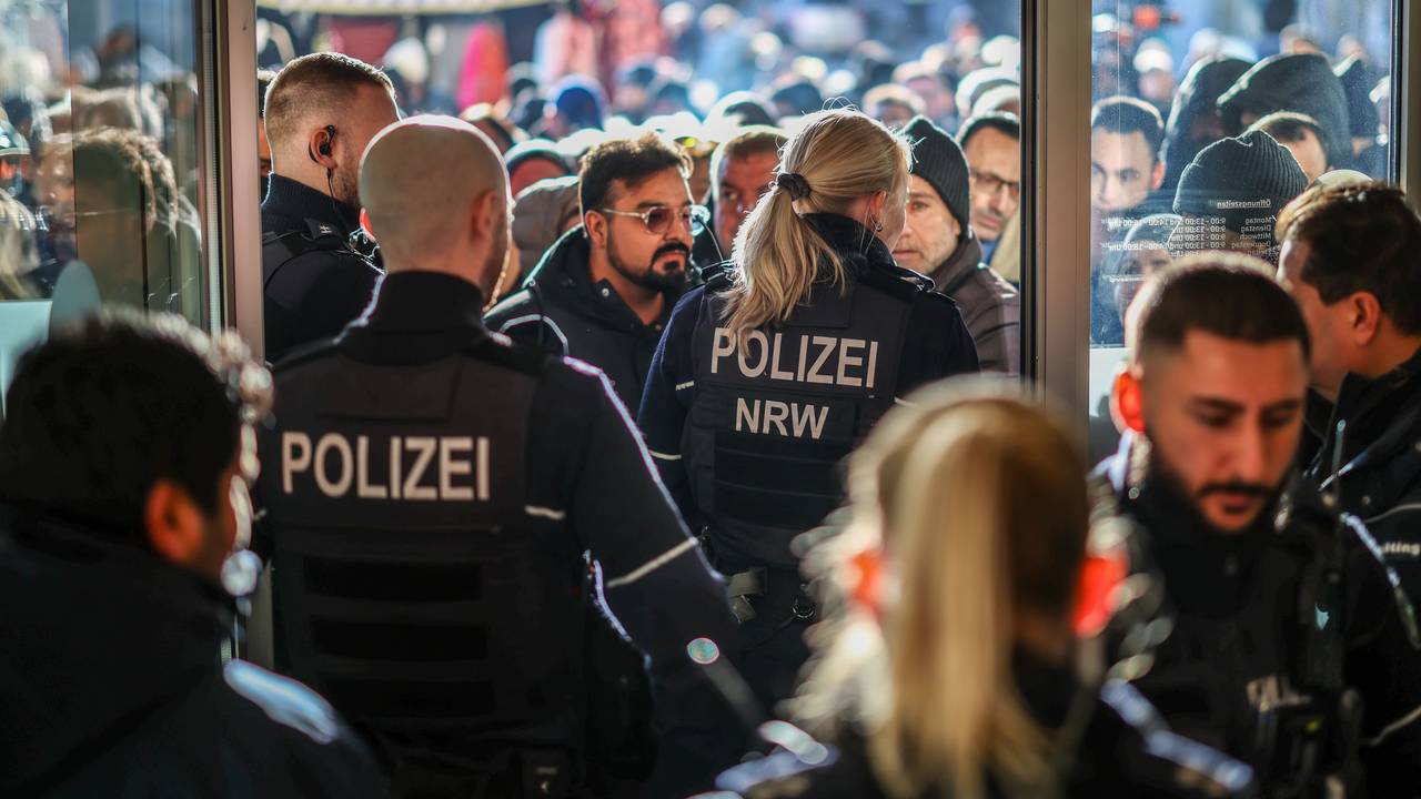 Menschen stehen vor dem Eingang zur Sparkasse, den Polizeikräfte versperren.
