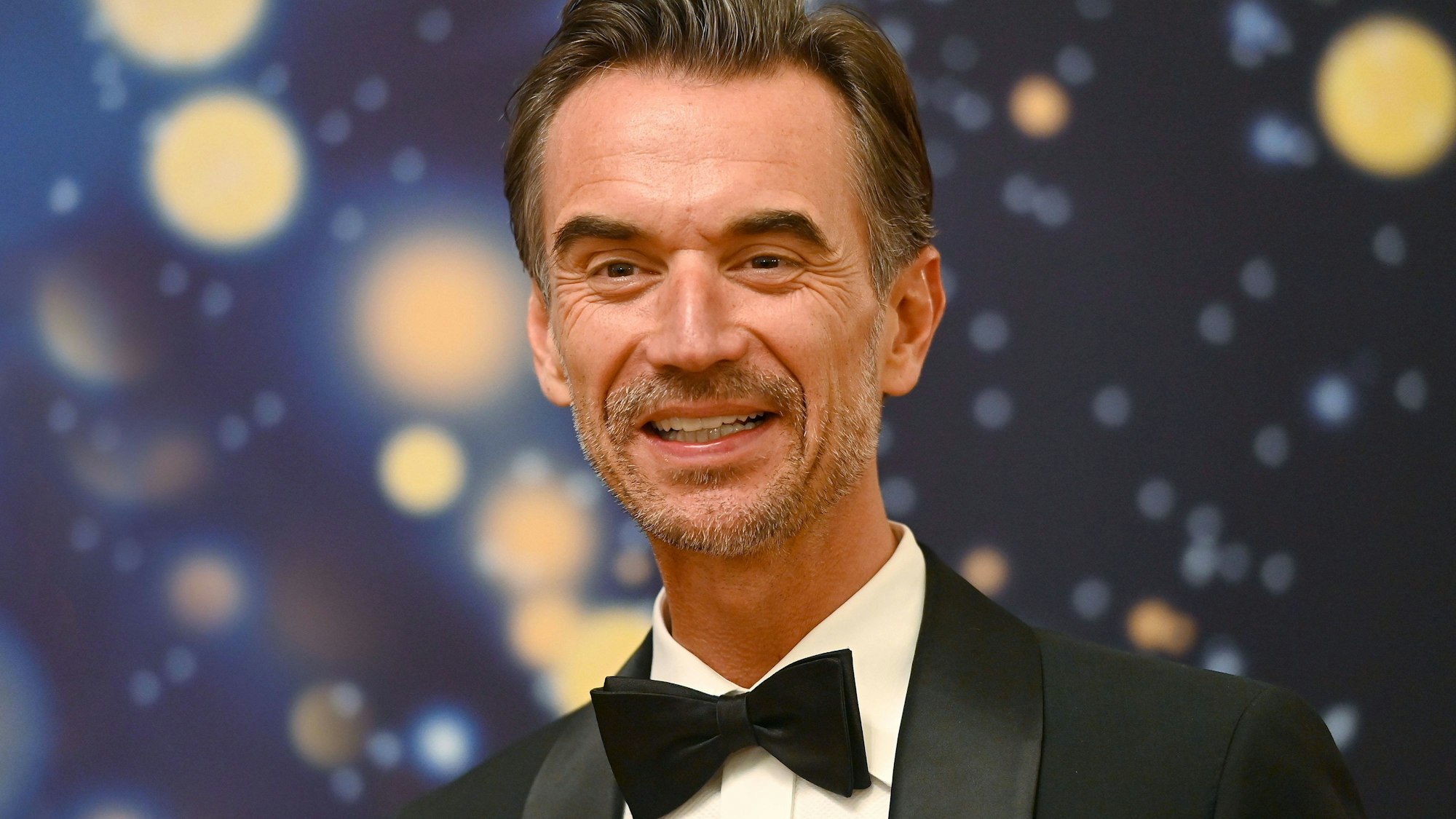 Florian Silbereisen im Anzug vor unscharfem Hintergrund