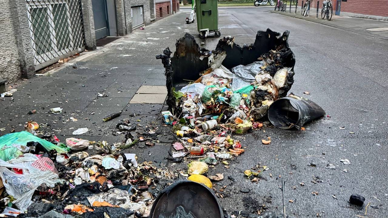 Zwei verbrannte Container liegen auf der Straße, zwischen ihnen der ganze Müll.