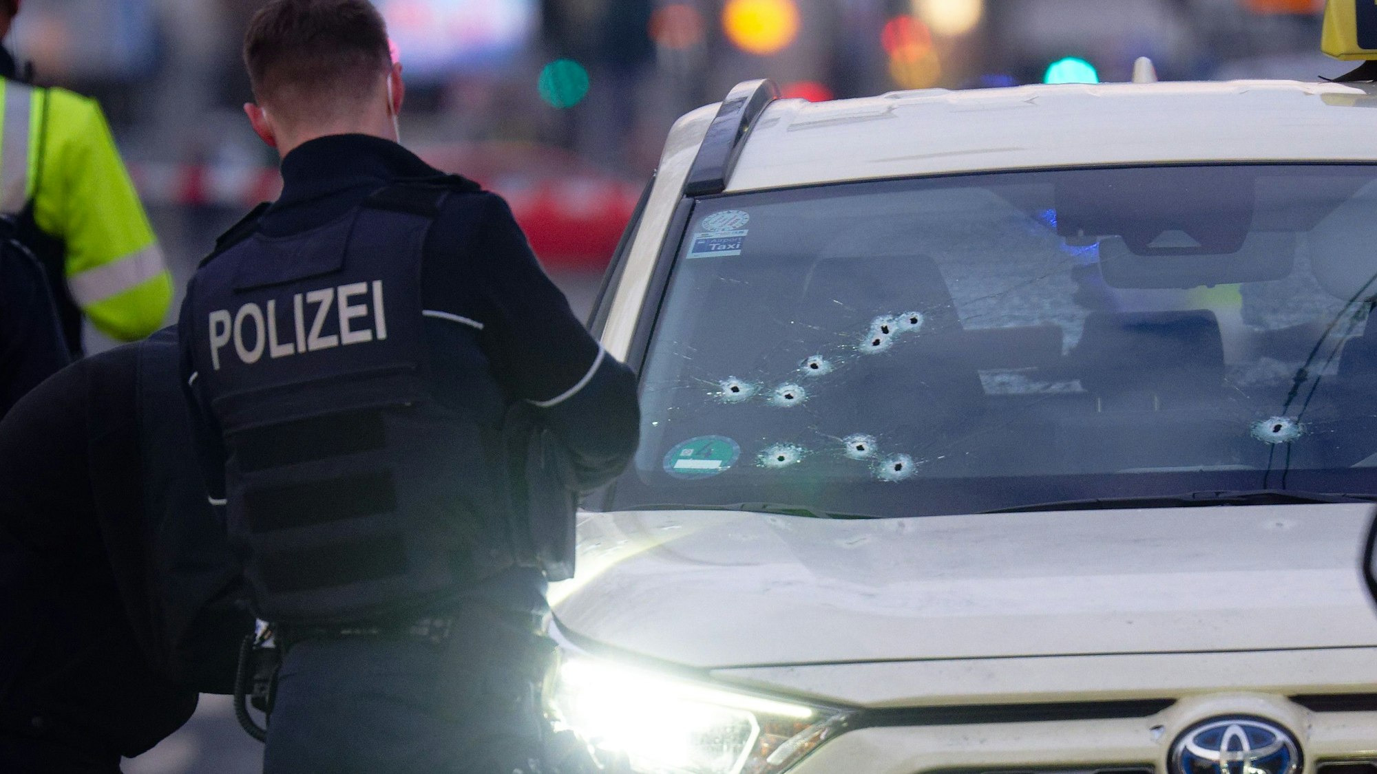Ein Taxi mit Schusslöchern in der Frontscheibe steht auf der Straße. V