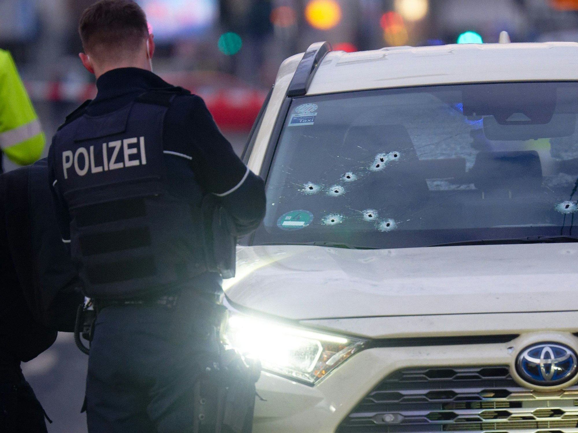 Ein Taxi mit Schusslöchern in der Frontscheibe steht auf der Straße.