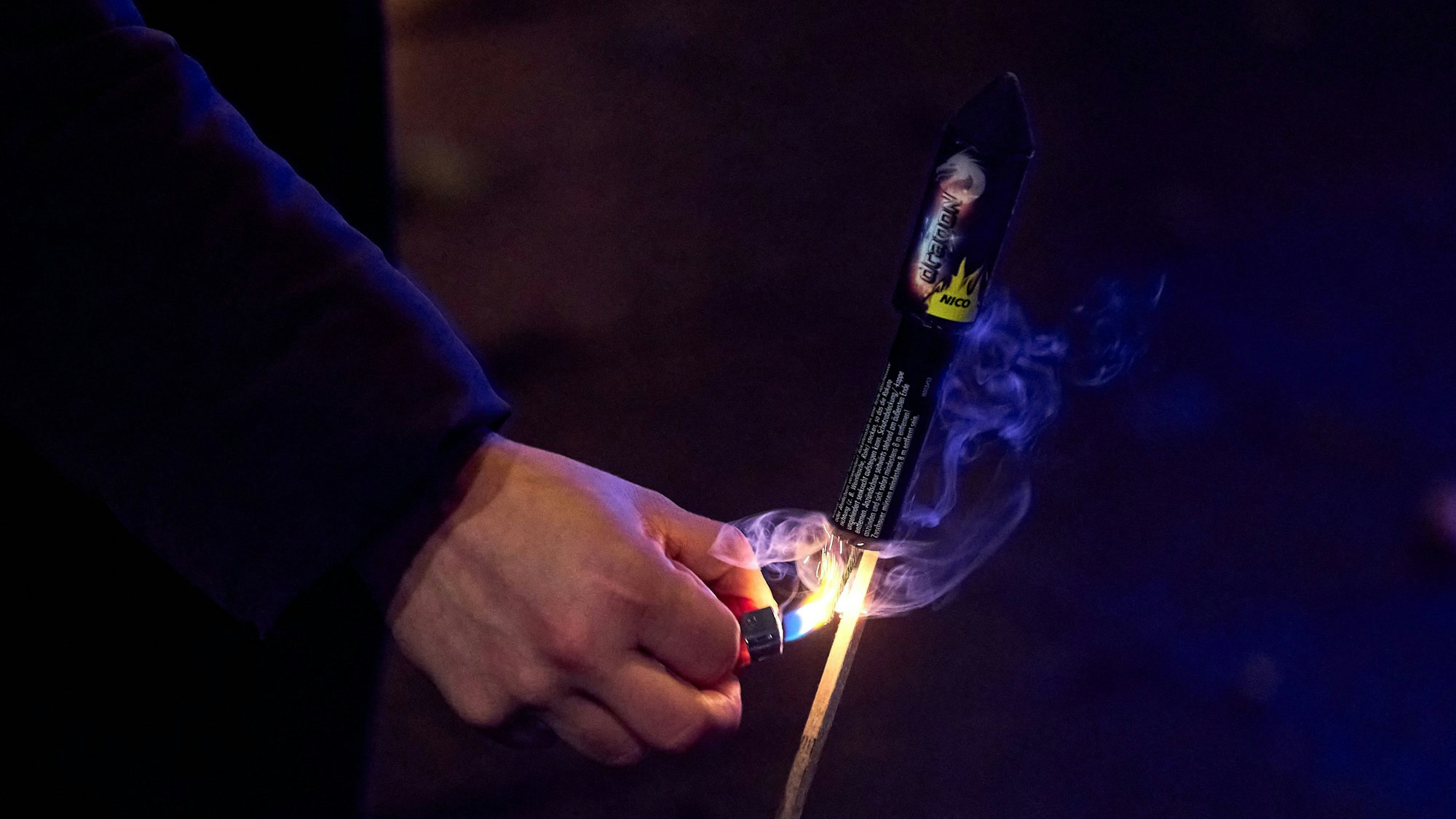 Menschenhand zündet Feuerwerksrakete an