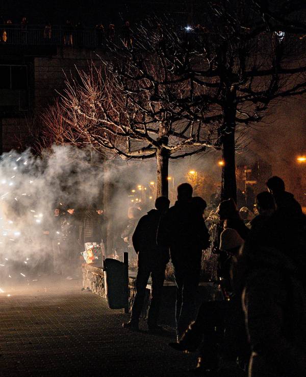 Feiernde zünden Feuerwerk in der Silvesternacht am Rheinufer an der Kennedybrücke.