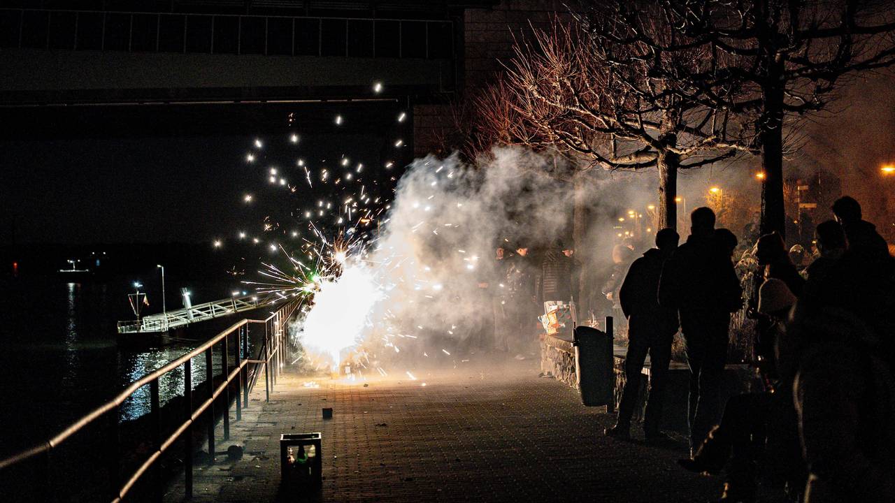 Feiernde zünden Feuerwerk in der Silvesternacht am Rheinufer an der Kennedybrücke.