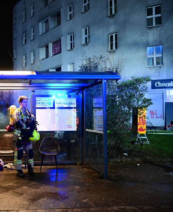 Erschöpfte Feuerwehrmänner stehen nach einem Einsatz während der Silvesternacht nach einer Brandbekämpfung in Berlin an einer Bushaltestelle.
