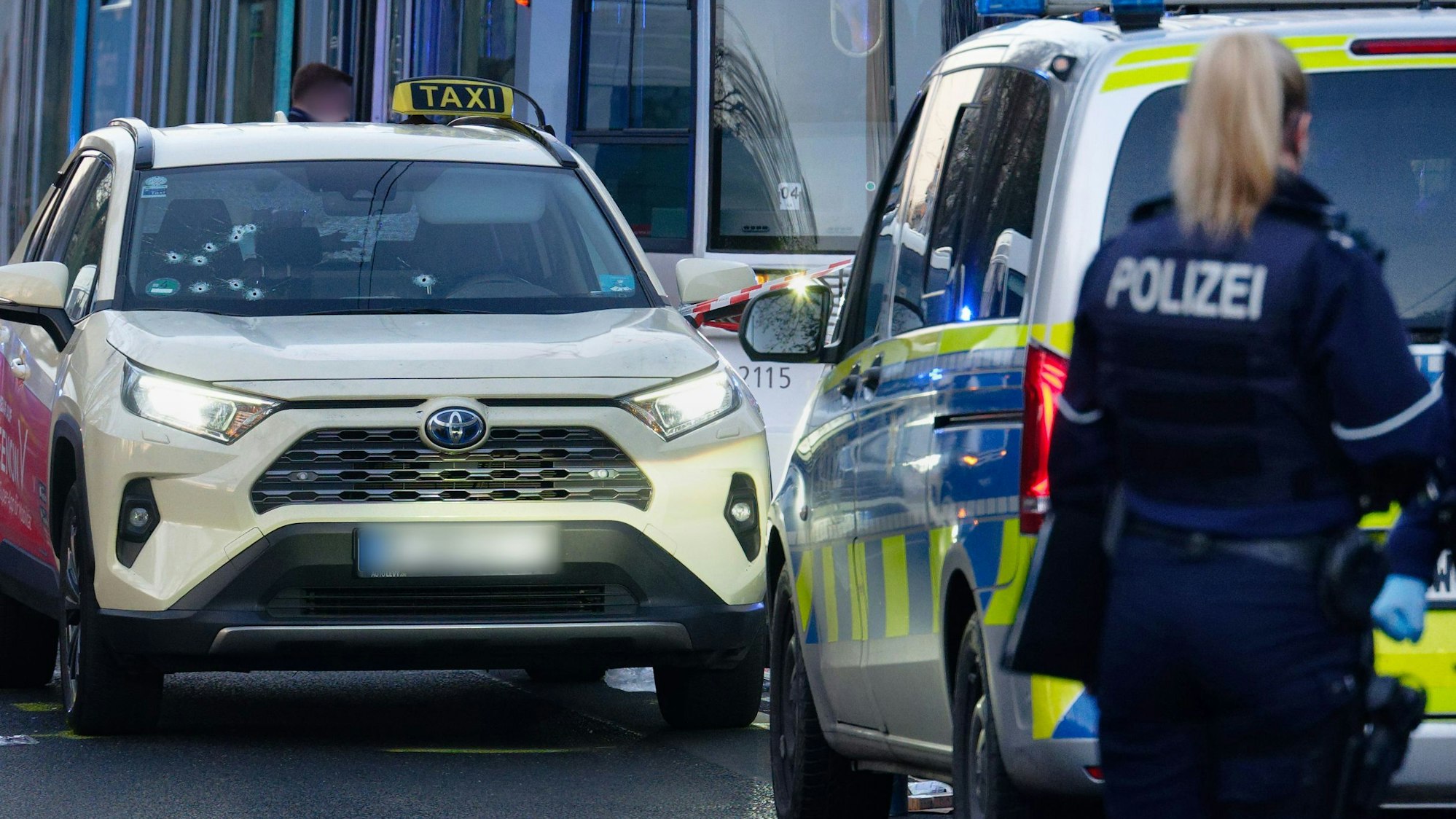 Ein Taxi mit Schusslöchern in der Frontscheibe steht auf der Straße.