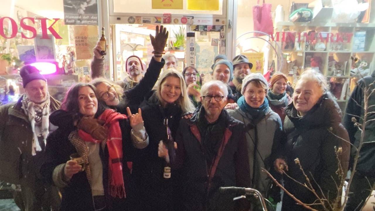 Eine Menschengruppe steht vor einem Kiosk.