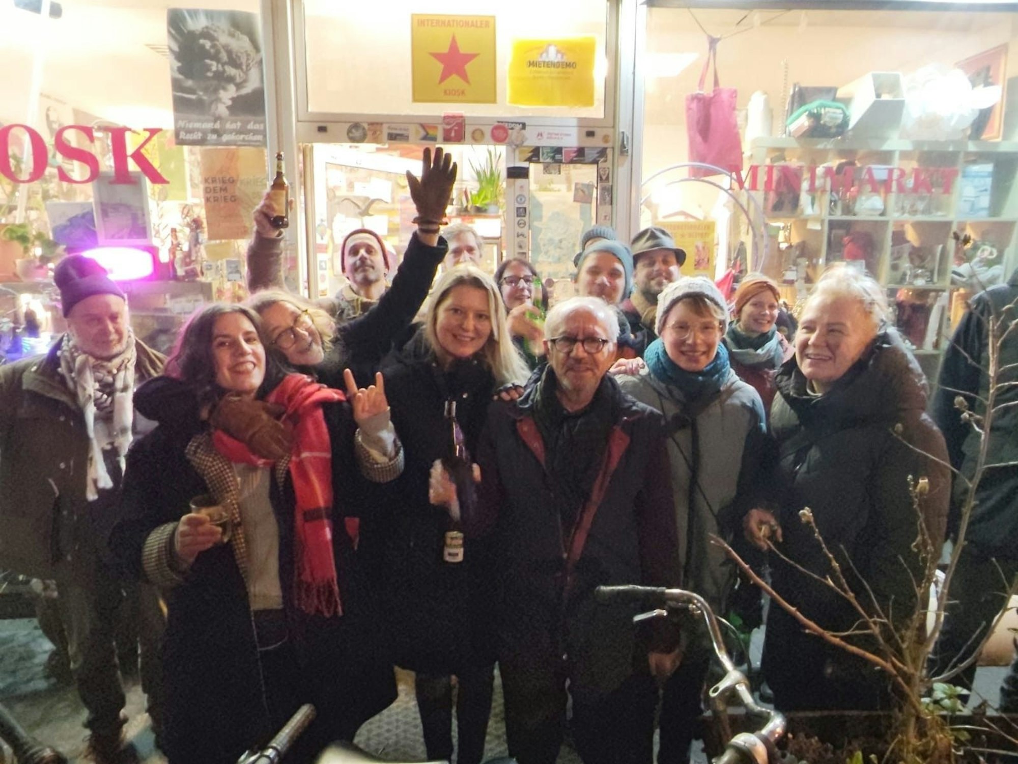 Eine Menschengruppe steht vor einem Kiosk.