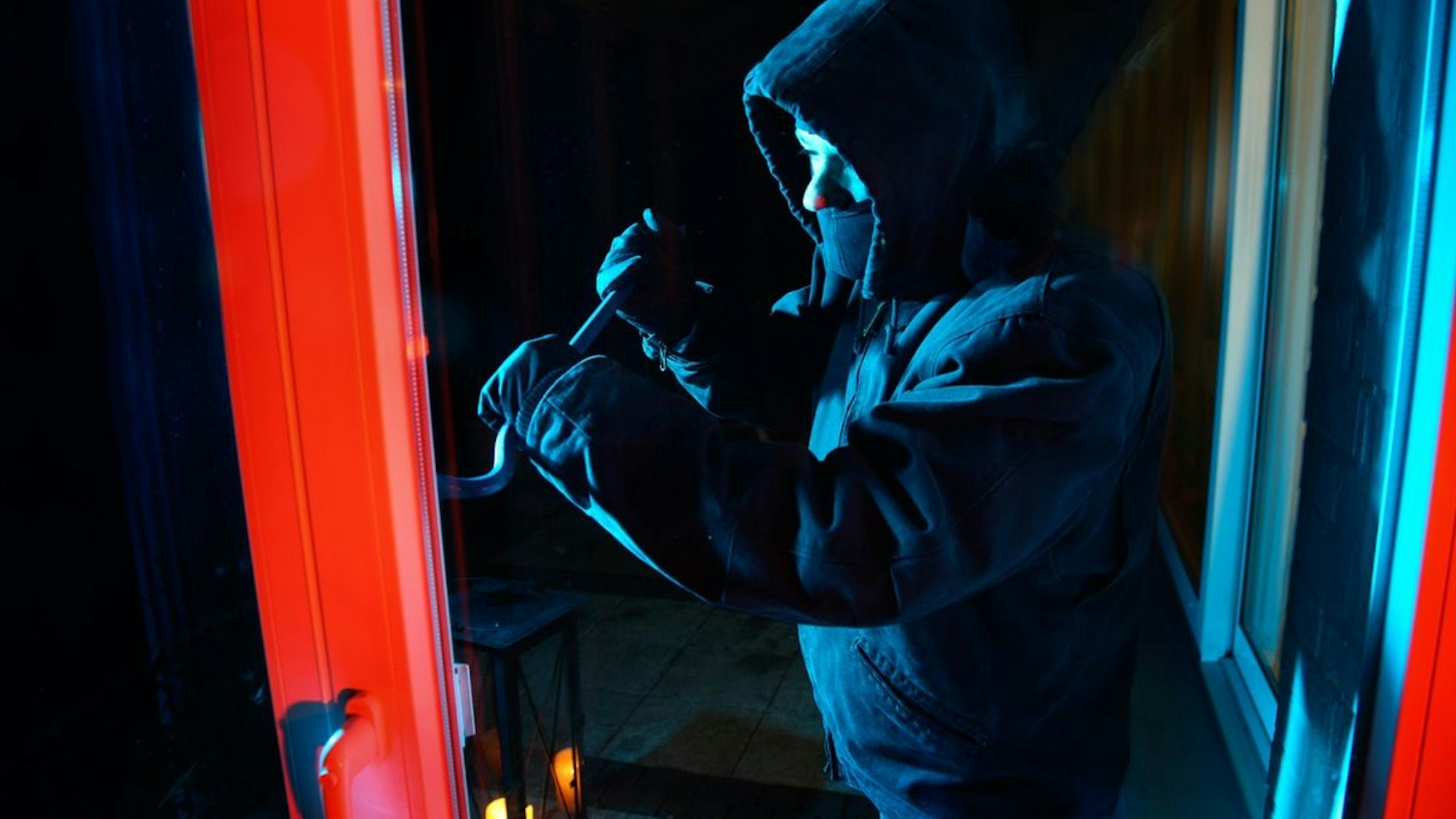 Einbrecher hebeln mit einem Brecheisen ein Fenster auf.