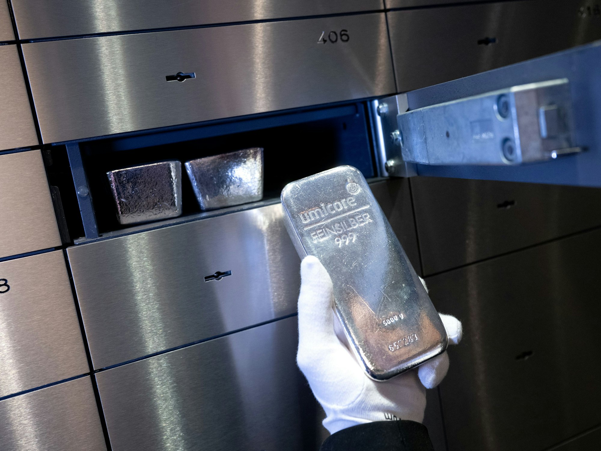 Das Symbolfoto zeigt einen Mann, der einen Silberbarren in ein Schließfach in einem Tresorraum legt.