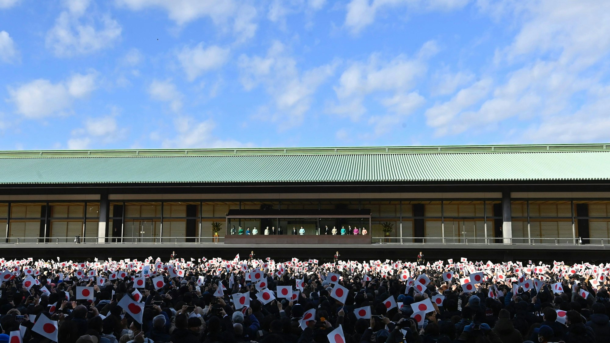Japanische Kaiserfamilie grüßt Menschen mit Flaggen