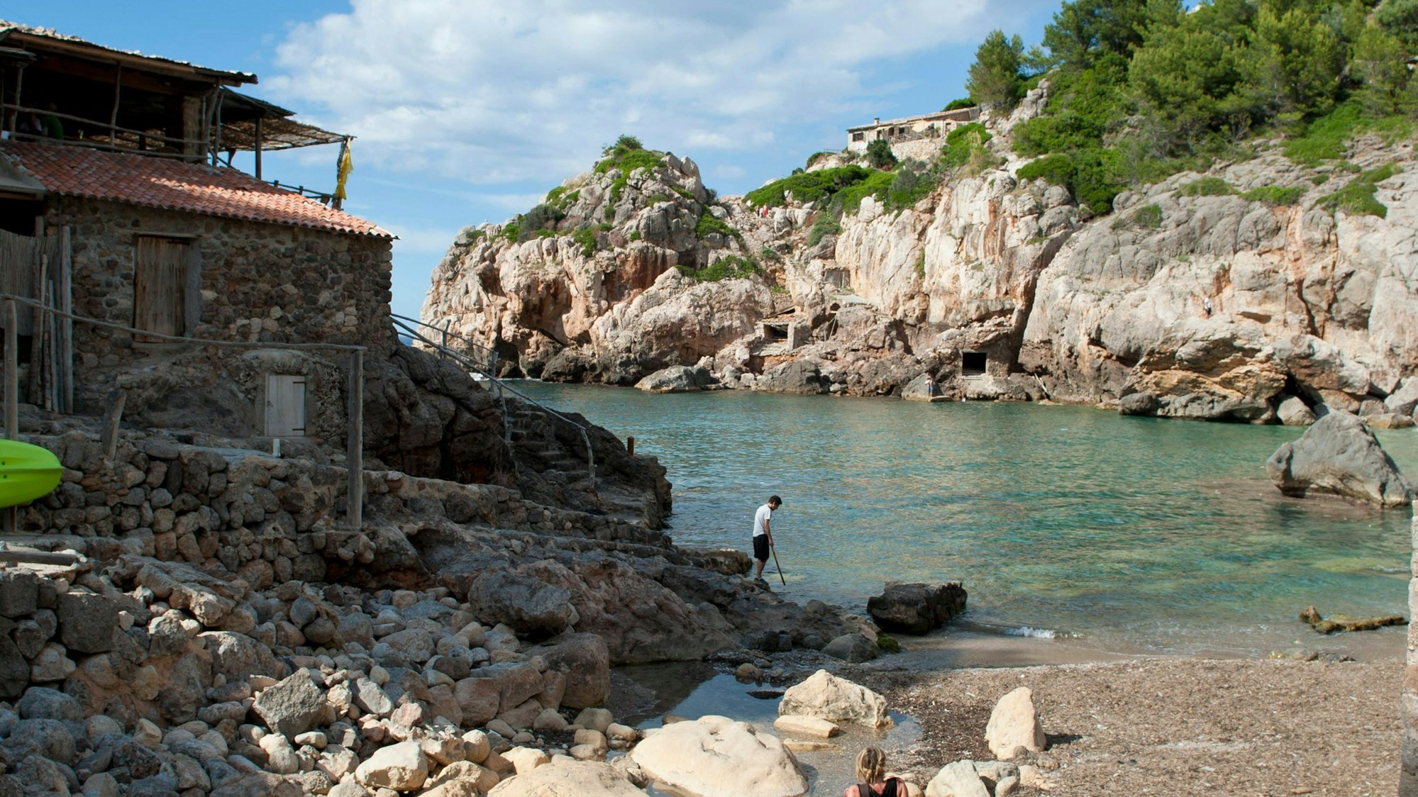 Felsige Bucht mit Boot, Häusern und Menschen