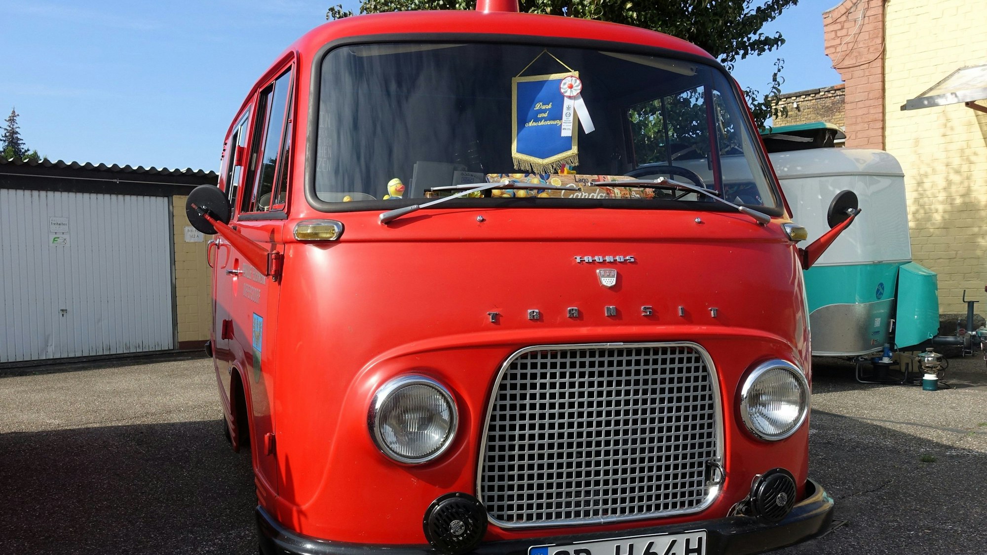Ein rotes Fahrzeug parkt an einem sonnigen Tag