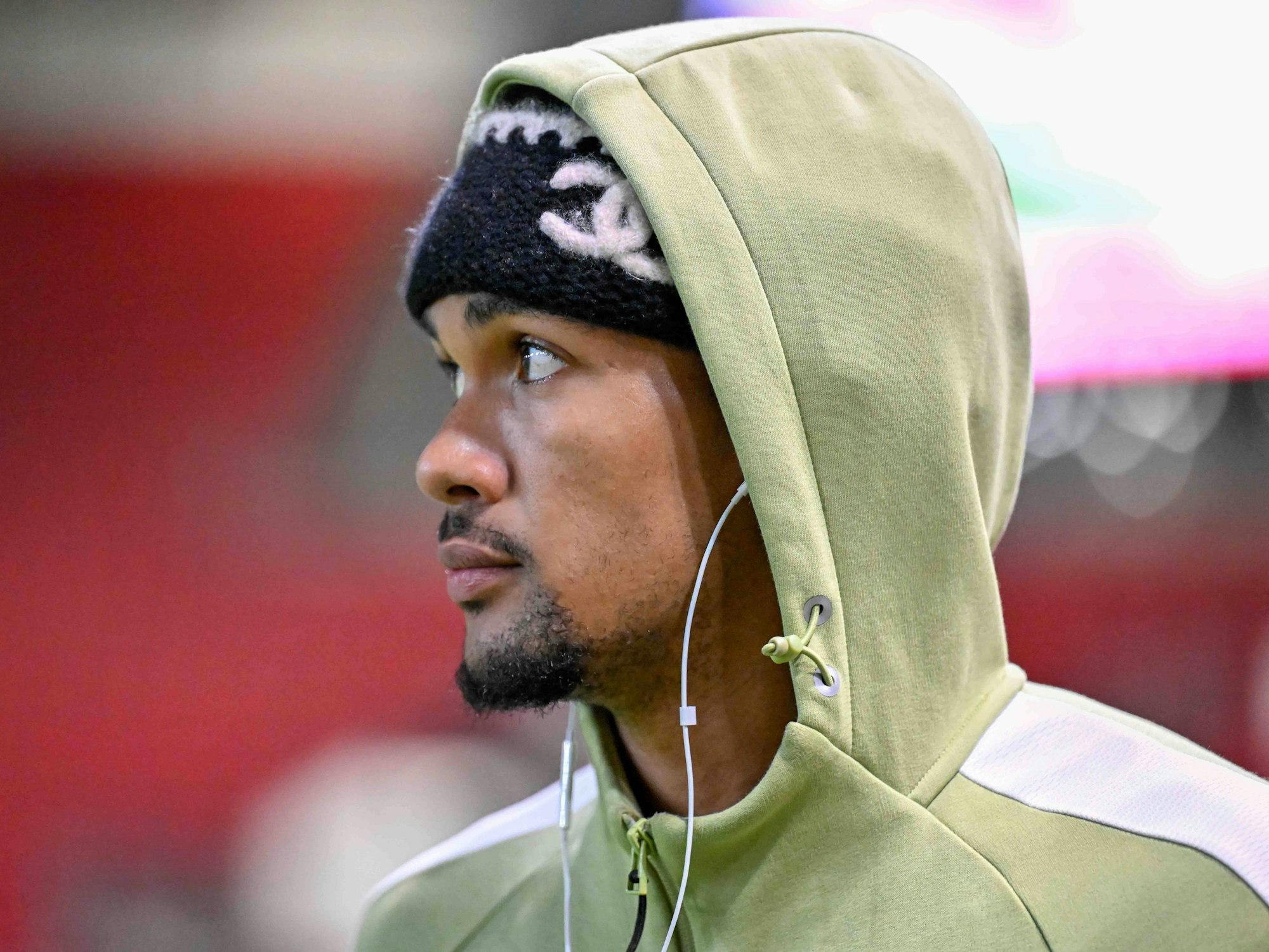 Damion Downs trägt einen Hoodie und Kopfhörer und schaut nachdenklich.