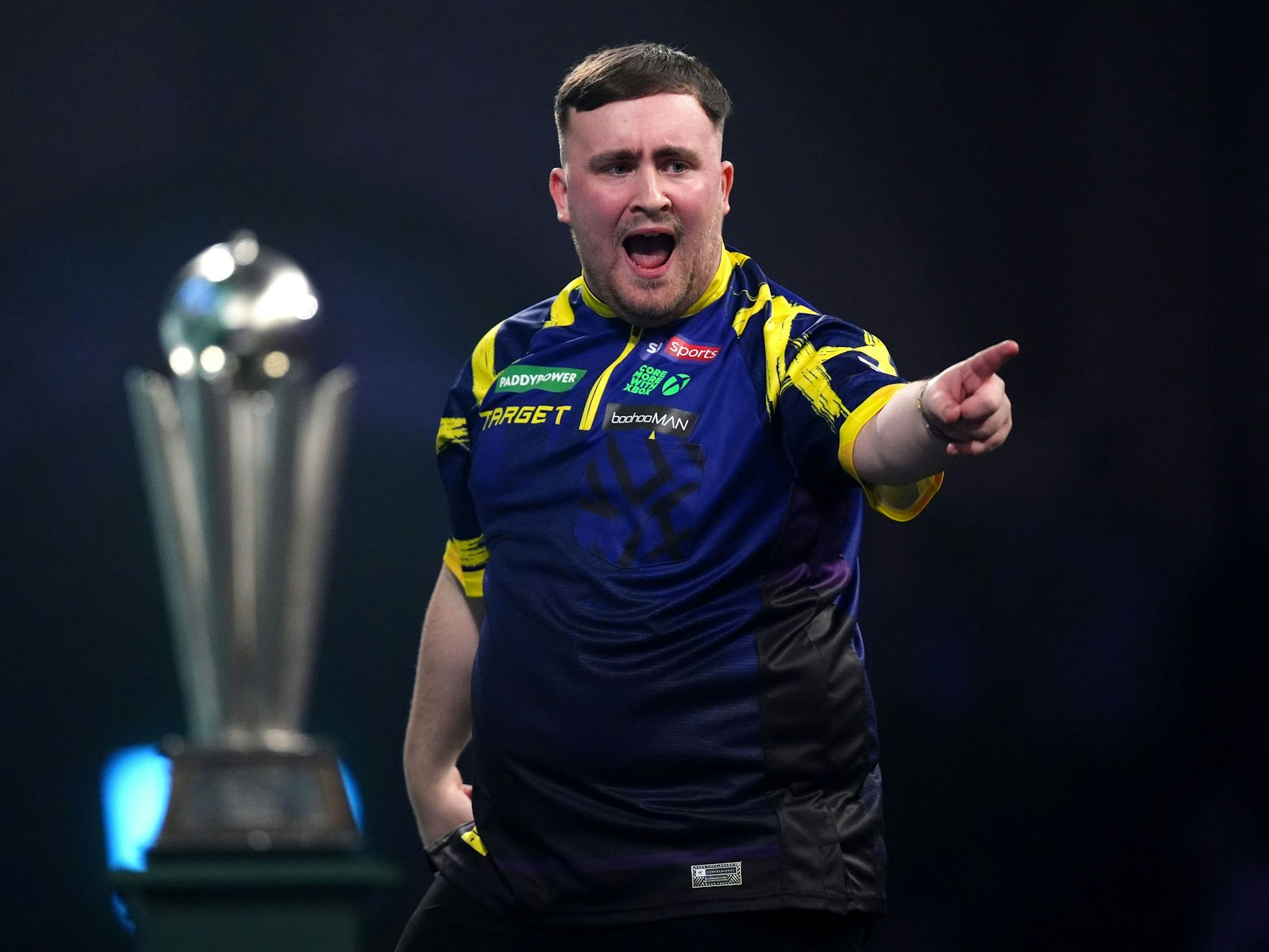 Luke Littler zeigt jubelnd mit dem Finger in Richtung Publikum.