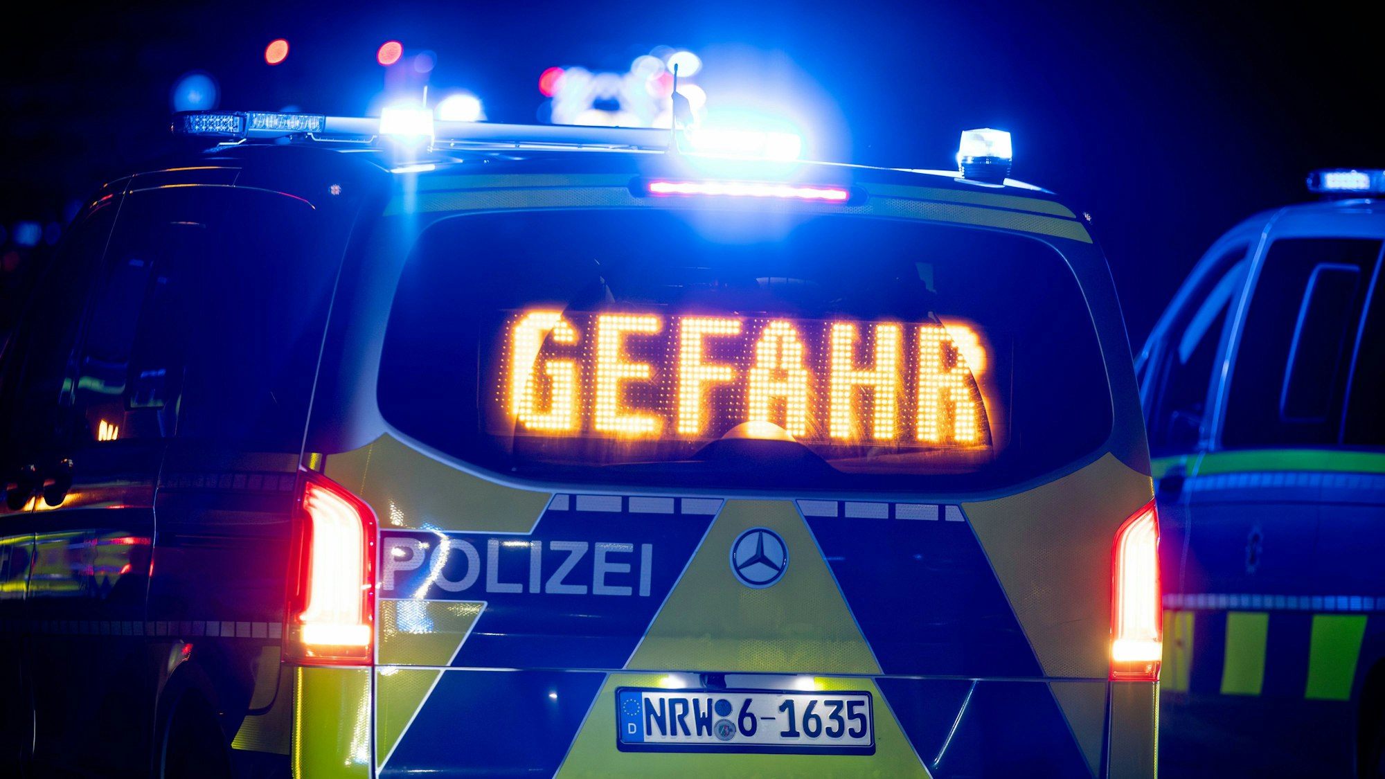 Polizeifahrzeug mit Blaulicht und Warnhinweis "Gefahr"
