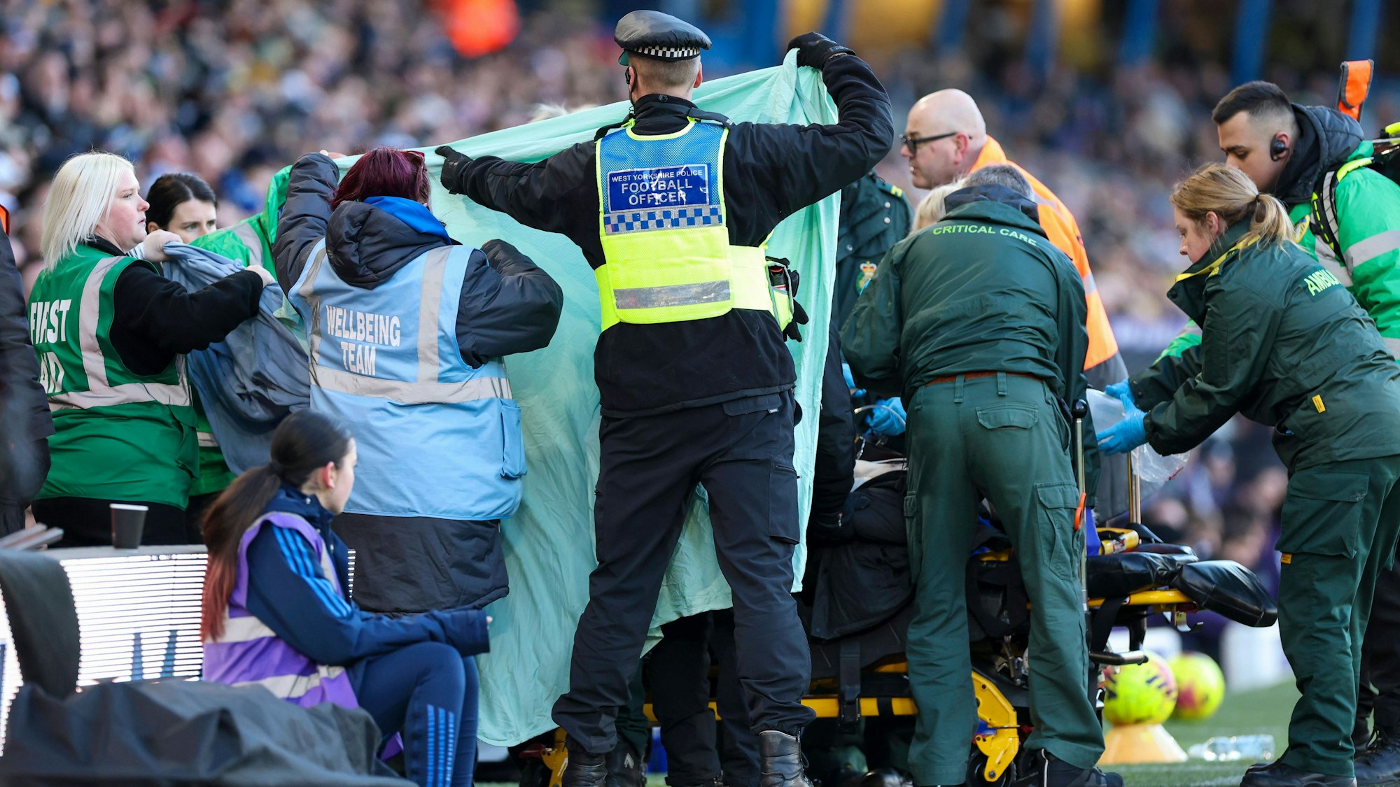 Polizisten und Stadionmitarbeiter halten einen Sichtschutz auf der Tribüne hoch.