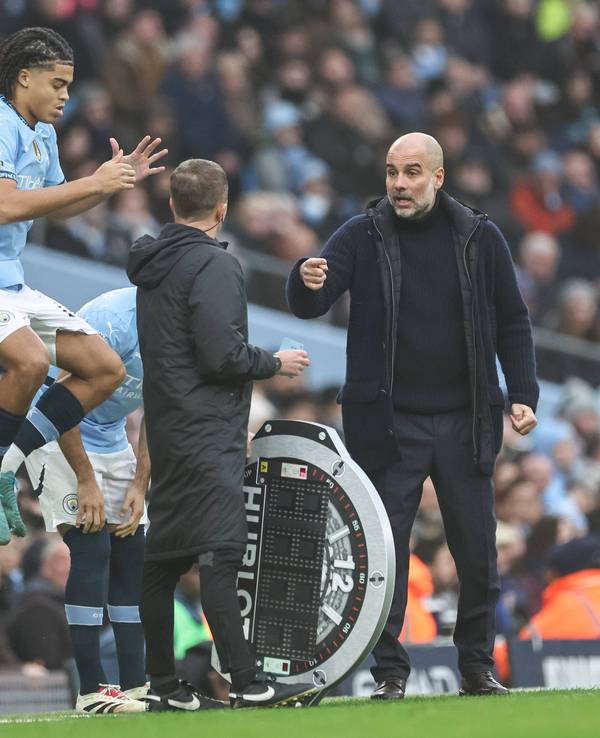 Jahmai Simpson-Pusey springt im Trikot von Manchester City in die Luft, Trainer Pep Guardiola gestikuliert dabei.