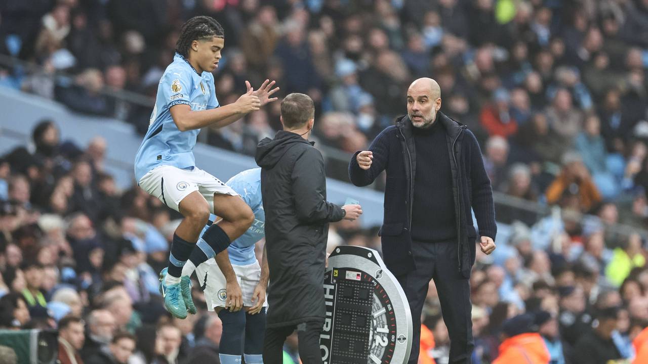 Jahmai Simpson-Pusey springt im Trikot von Manchester City in die Luft, Trainer Pep Guardiola gestikuliert dabei.