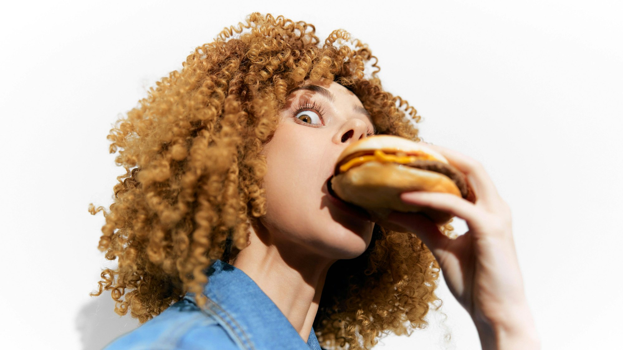 Eine Frau beißt in einen Burger (Symbolfoto)