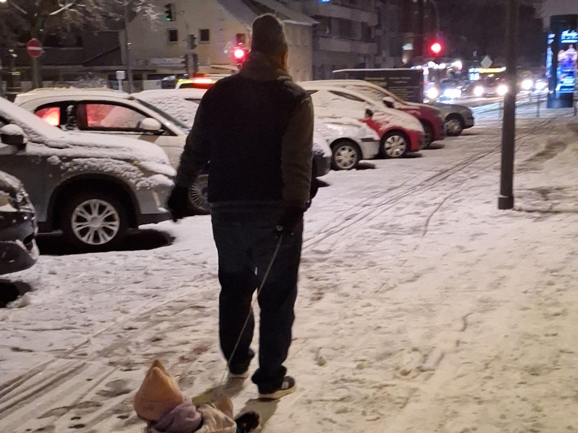 Ein Mann zieht ein Kind auf einem Schlitten.