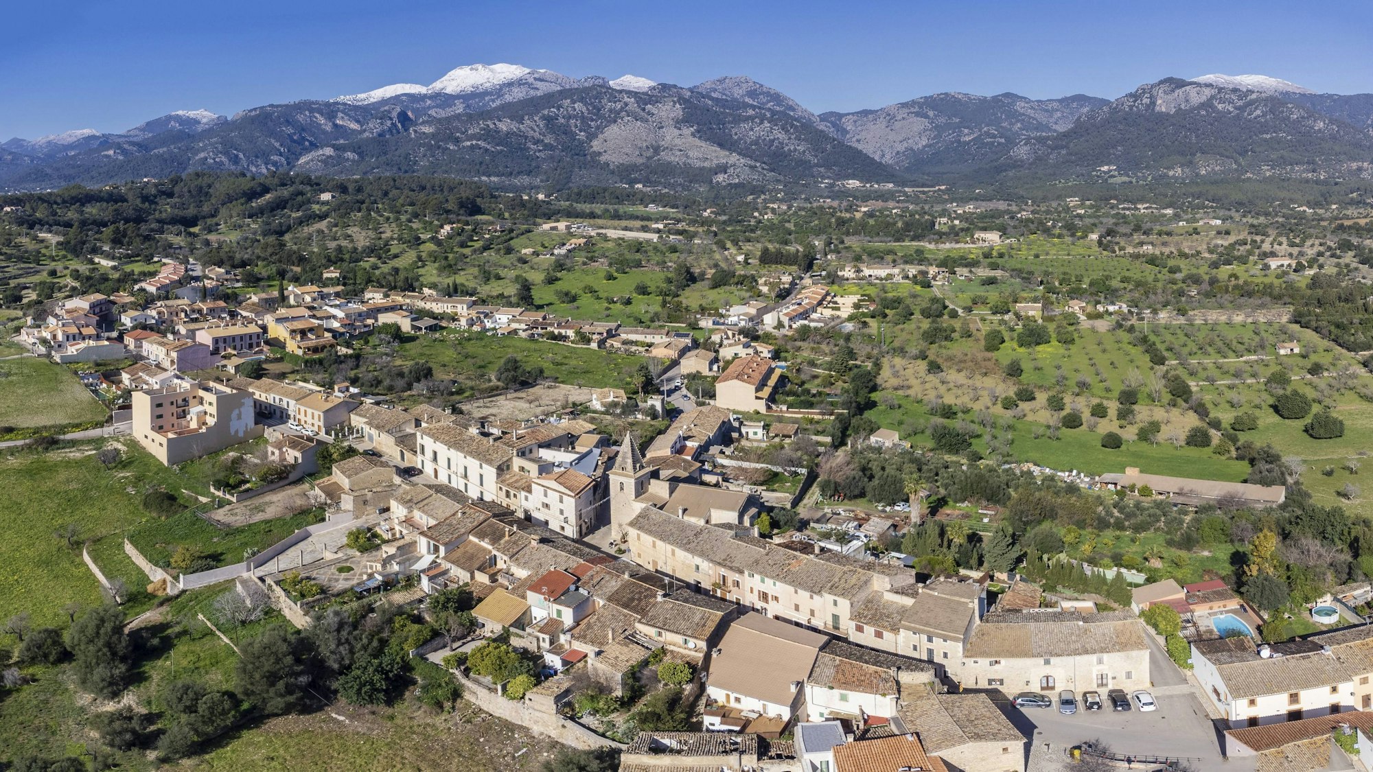 Luftaufnahme eines Dorfes mit verschneiten Bergen auf Mallorca
