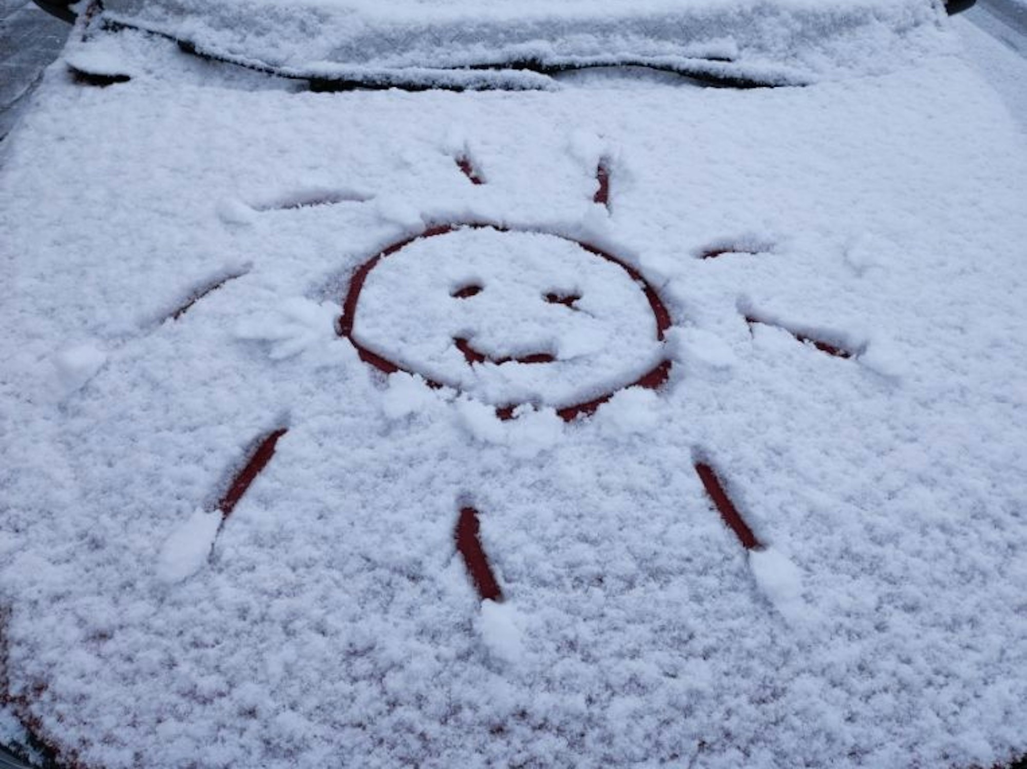 Ein Schneegesicht auf einem Auto in Köln.