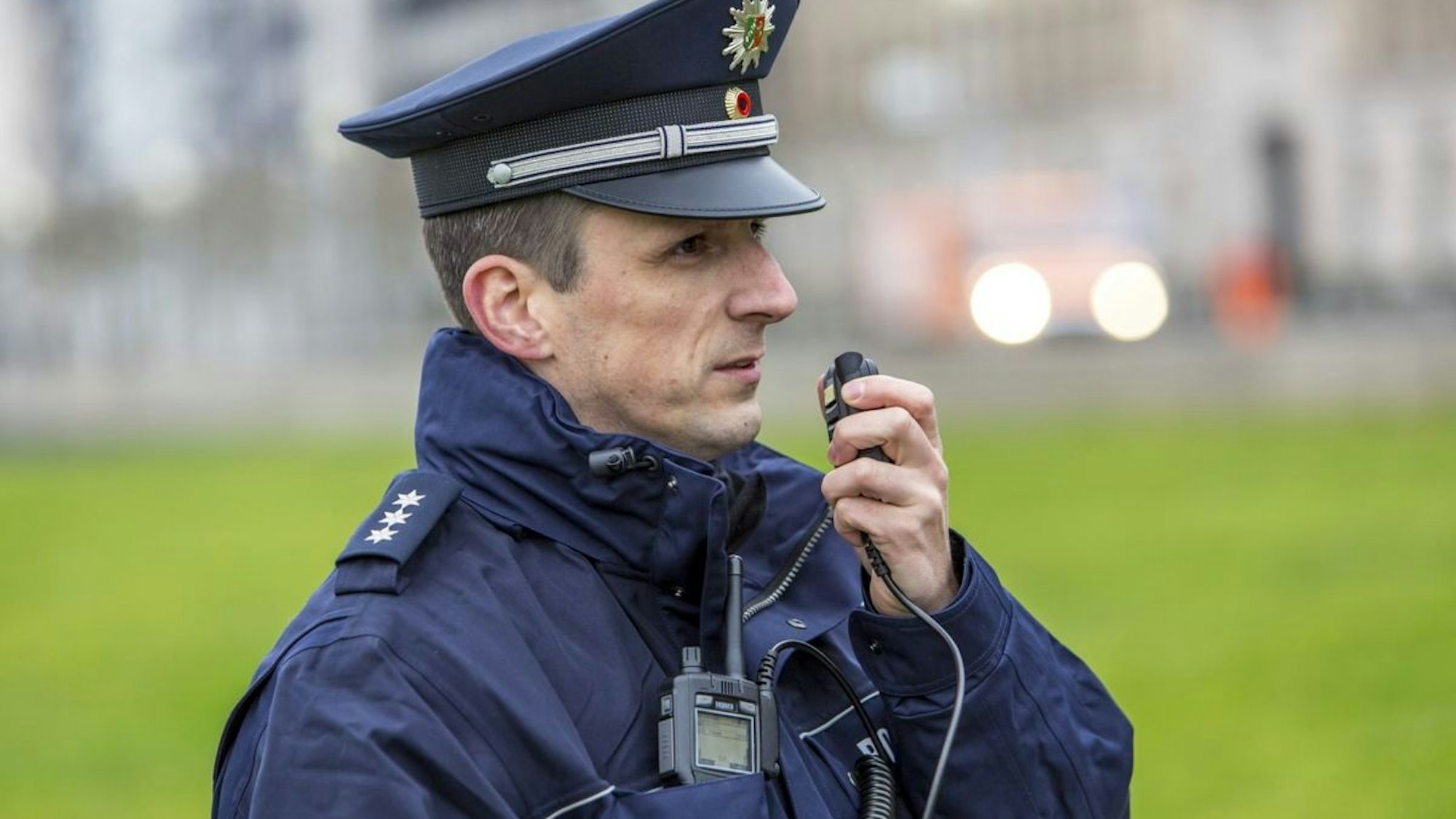 Ein Polizist steht neben einem Polizeiauto.