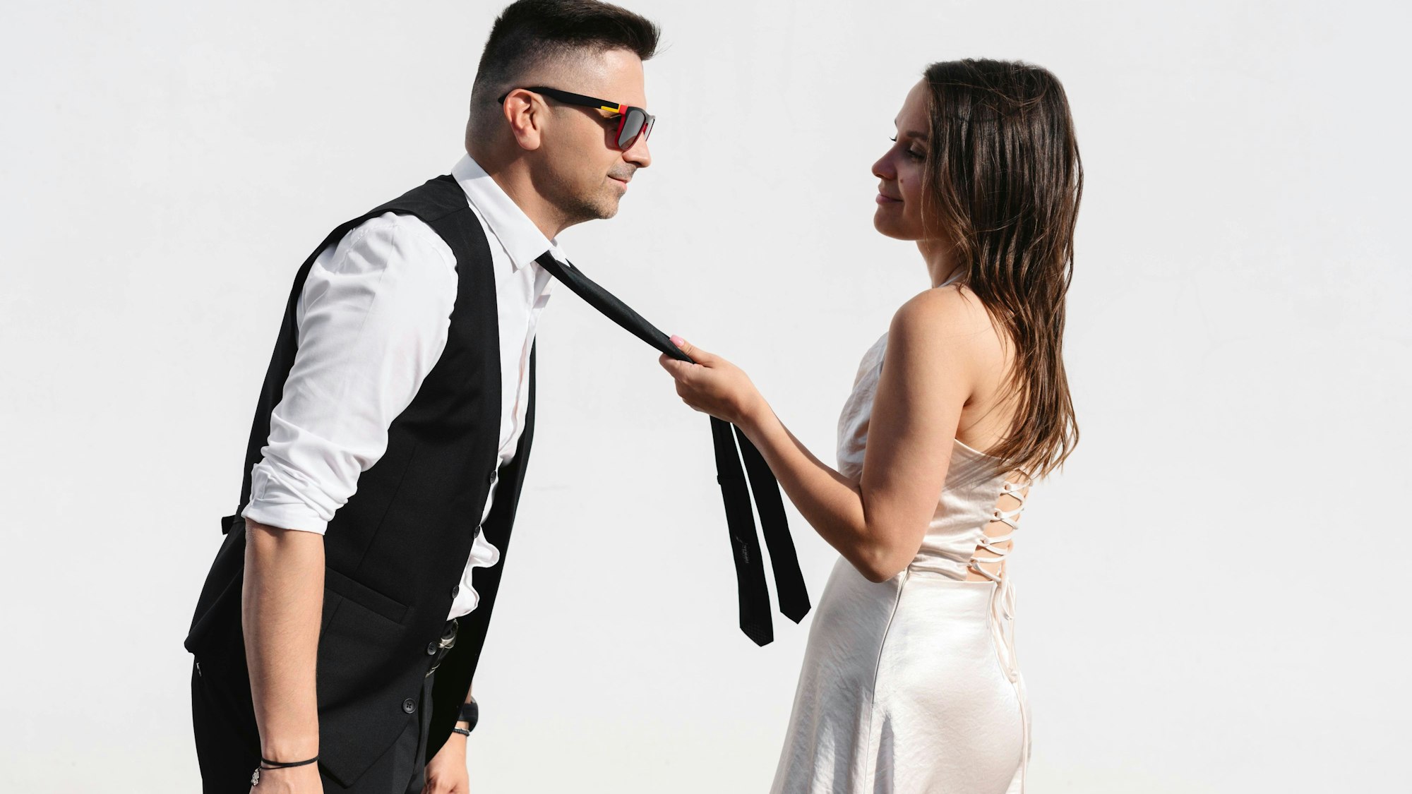 Brautpaar steht, die Frau hält die Krawatte des Mannes