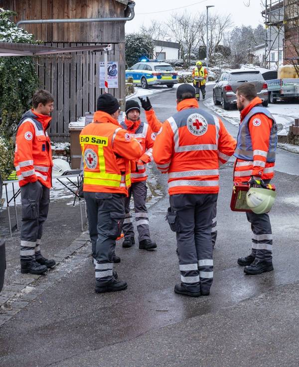 Einsatzkräfte stehen nahe der Unglücksstelle, nachdem während eines Einsatzes der Feuerwehr und des Rettungsdienstes wegen eines medizinischen Notfalls ein Treppenhaus in einem Einfamilienhaus eingestürzt war.