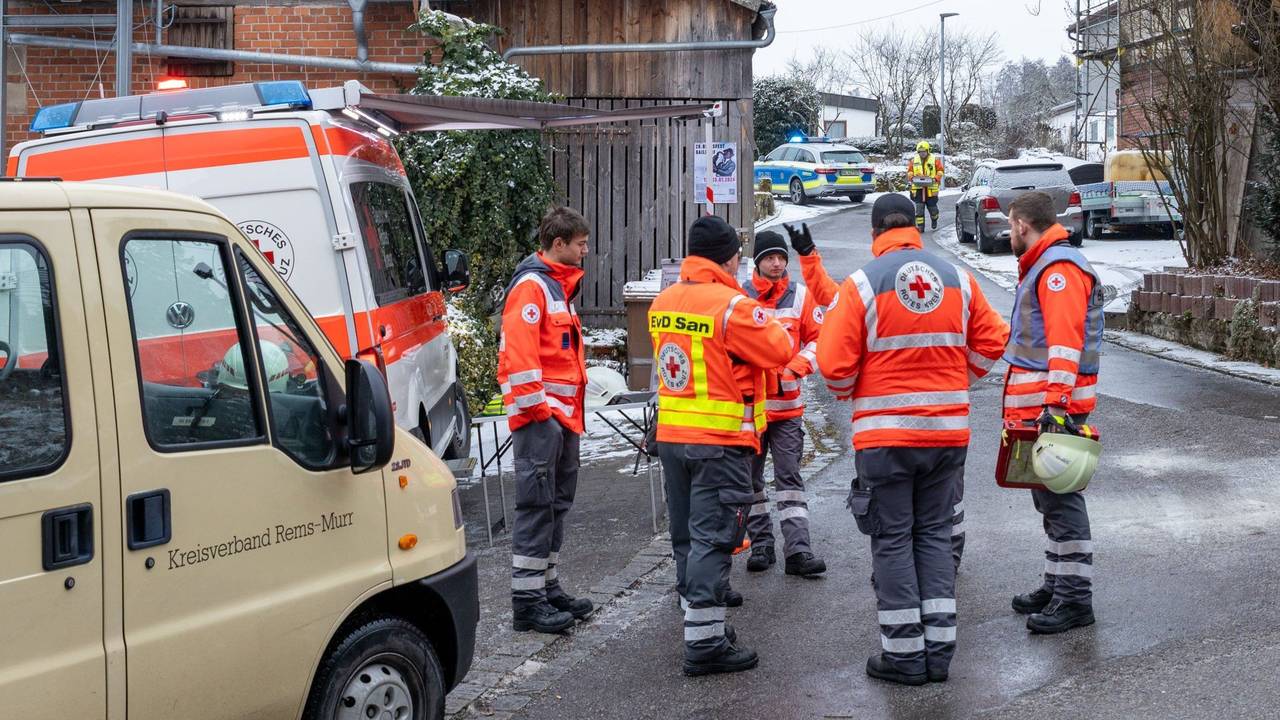 Einsatzkräfte stehen nahe der Unglücksstelle, nachdem während eines Einsatzes der Feuerwehr und des Rettungsdienstes wegen eines medizinischen Notfalls ein Treppenhaus in einem Einfamilienhaus eingestürzt war.