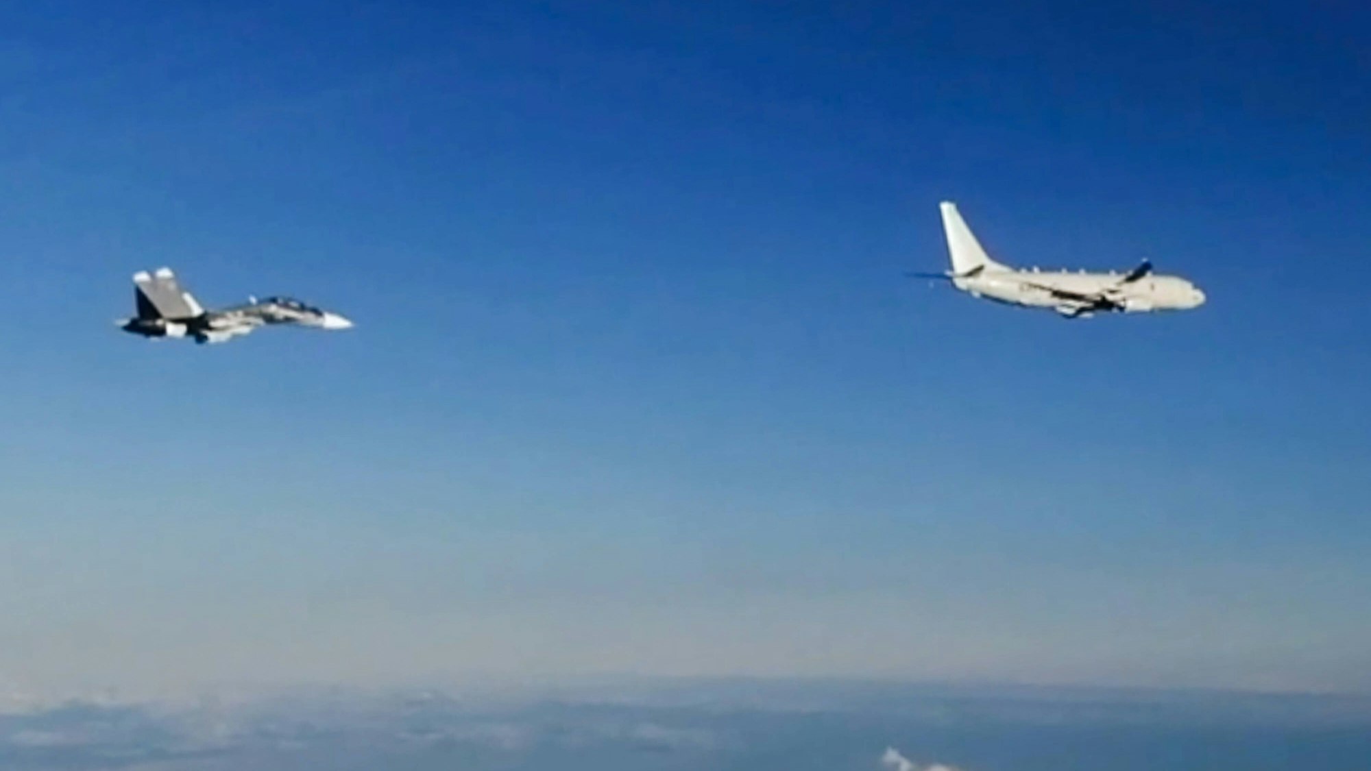 Eine P-8 Poseidon der US Air Force fliegt begleitet von einem russischen Su-30 Kampfjet über dem Schwarzen Meer.