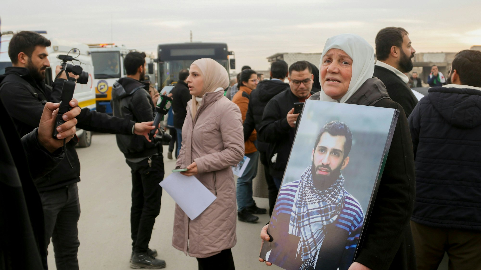 Menschen bei einer Versammlung, eine Frau hält ein Bild