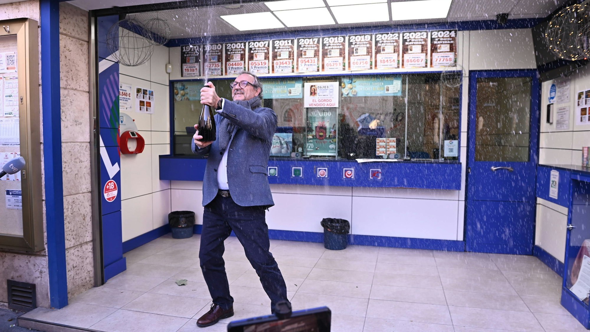 Jemand sprüht Flüssigkeit aus Flasche in einem Raum