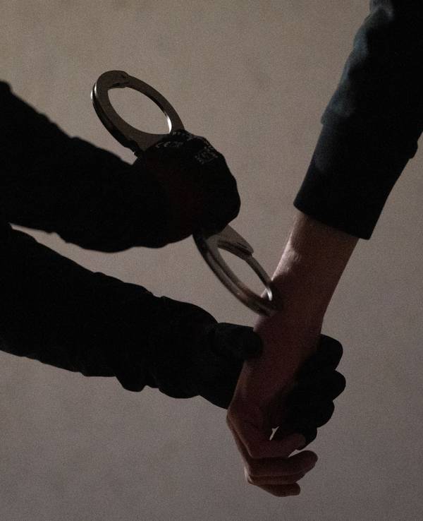 Das Symbolfoto zeigt eine Beamtin, die einem Verdächtigen Handschellen anlegt.