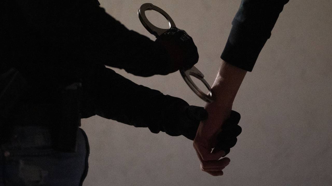 Das Symbolfoto zeigt eine Beamtin, die einem Verdächtigen Handschellen anlegt.