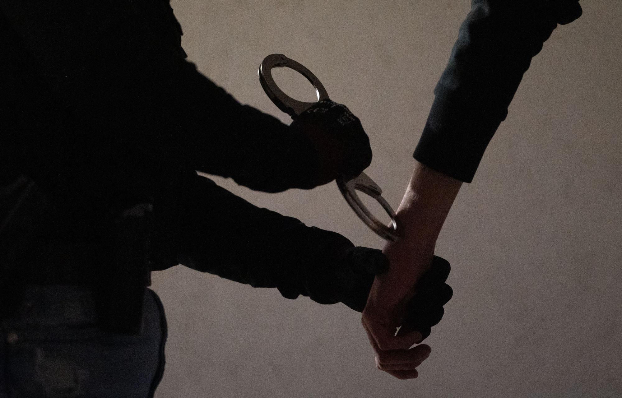 Das Symbolfoto zeigt eine Beamtin, die einem Verdächtigen Handschellen anlegt.