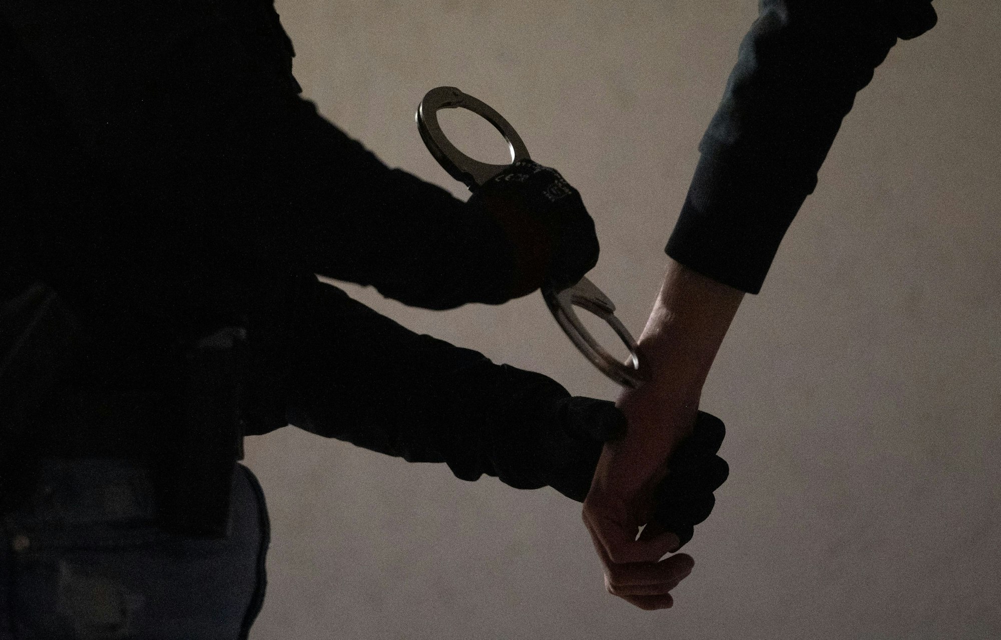 Das Symbolfoto zeigt eine Beamtin, die einem Verdächtigen Handschellen anlegt.