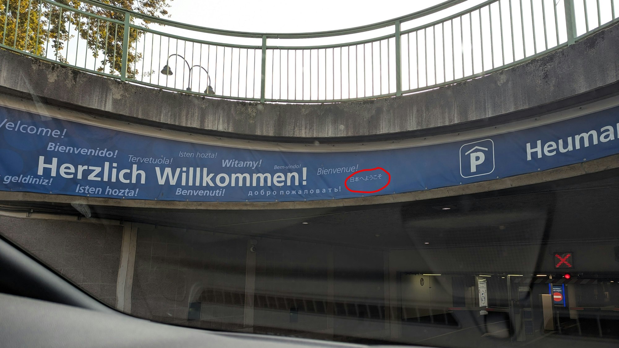 Auf einem Schild steht das Willkommen in verschiedenen Sprachen, ein japanischer Schriftzug ist eingekringelt worden.